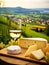 Cheese board and white wine against the backdrop of village. AI