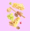 Cheese, breadstick, grapes and walnuts falling against violet background