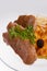 Cheese casserole with slises of grilled meat on white background on a transparent plate, close up