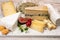 Cheese collection, marble board with French cheeses brie, tomme, matured goat cheese, morbier served with fresh raspberries and