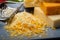 Cheese collection, matured and orange original British cheddar cheese in blocks and grated served on grey plate