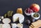 Cheese, crackers, pear, dill pickles, olives, figs and caper berries on black background with space for text