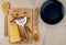 Cheese on a cutting Board with spices and a grater and spatulas with pasta and a blue plate on a wooden background