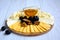 Cheese of different varieties and shapes, grapes, walnut lie on a wooden plate on a light background