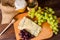 Cheese with grapes, olive, honey on wood