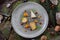 Cheese Harmony: Gray Plate Amidst New Year\\\'s Greenery and Nuts