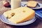 Cheese, milk, eggs and bread on a rustic wooden table, with a fi