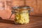 Cheese pate with garlic in a transparent jar on a wooden table at sunny kitchen.