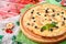 Cheese pizza with chicken and olives on a round wooden board on a red wooden background, decorated with napkins