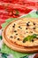 Cheese pizza with chicken and olives on a round wooden board on a red wooden background, decorated with napkins