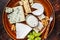 Cheese plate with Brie, Camembert, Roquefort, blue cream cheese, grape and nuts. Dark background. Top view