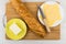 Cheese in plate, butter, knife, bread on cutting board