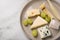 Cheese plate platter with selection Edamer, Parmesan, goat, blue and cream cheese, peer and grapes on marble background