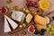 Cheese plate. Various types of cheese with grapes, honey, figs and nuts on rustic wooden table.