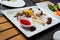 Cheese plates served with grapes, jam, and nuts on a white plate.