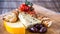 Cheese platter, antipasto, marinated olives, tomatoes and crackers on wooden board, closeup.