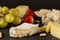 A cheese platter containing a selection of aged artisan French, Italian and Swiss cheese assortment on black cheese board