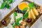 Cheese platter garnished with honey, walnuts, grapes, bread, mint and glass of wine over wooden background