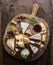 Cheese platter with organic cheeses, fruits, nuts and wine on wooden background. Top view. Tasty cheese starter