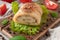 Cheese roll with olive herbs on a lettuce sheet. On a wooden board. Close-up. Decorated with arugula, spices and tomatoes.