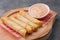 Cheese rolls plate with cocktail sauce served in a wooden plate on a rustic ba