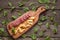Cheese and salami on kitchen board on rustic background. Top view with copy space and herbs .