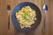 cheese spaetzle in black plate served with onion and chives with cutlery