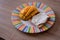 Cheese spread toasts with mango cut in cubes on a colorful plate on a wooden table