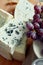 Cheese still life with red grapes and walnuts