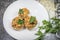 Cheese stuffed mushroom appetizer garnished with parsley on a white plate