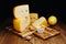 Cheese on the table, dark background. Medium hard cheese head edam, gouda, parmesan with jar of honey on wooden cutting