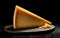 Cheese triangle on dark wooden board over black background