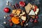 Cheese variety board or platter with cheese assortment, grapes, honey, nuts. Black stone background. Top view