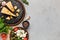 Cheese variety, olives and fresh herbs on concrete background.