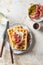Cheese waffles with ham, cream cheese and cucumber with cutlery on beige textured background. Delisious savory breakfast
