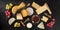 Cheese and wine panorama, various cheeses, shot from above on a black background