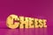 Cheese word written in actual Swiss cheese letters on magenta