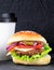 Cheeseburger and cup of coffee on a black stone background. Hamburger with cheese. Burger isolated. Tasty Dinner.Copy space