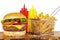 Cheeseburger with french fries basket, ketchup and mustard bottles.