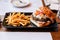 Cheeseburger with grilled beef, feta cheese and sliced tomato served with fries in black plate