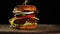 Cheeseburger with tomatoes, onions, barbecue cutlet and sesame bun on an old wooden cutting board, black background