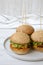 Cheeseburgers on grey plate over white wooden background, low angle view