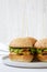 Cheeseburgers on grey plate over white wooden background. Side view. Close-up