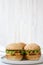 Cheeseburgers on grey plate over white wooden background, side view. Close-up