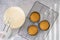 Cheesecake recipe. Three mini round cake pans tin, mould, with crushed crackers, and cheesecake batter in a bowl, view from