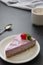 Cheesecake slice with berries and coffee cup, pink cheesecake isolated on dark background, dessert or breakfast. Sweet food