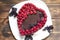 Cheesecake for vegans with love. Topped with raspberries, on white plate with basil leaves. made in shape of a heart