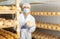 Cheesemaker in mask controlling maturing process of cheese wheels