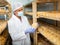 Cheesemaker in mask controlling maturing process of cheese wheels