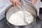 Cheesemaker mixes curdled milk with a whisk